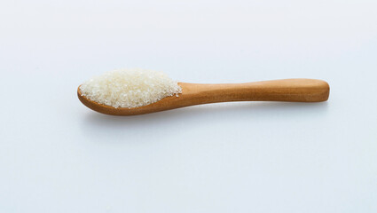 Wooden spoon with sugar crystals on white background