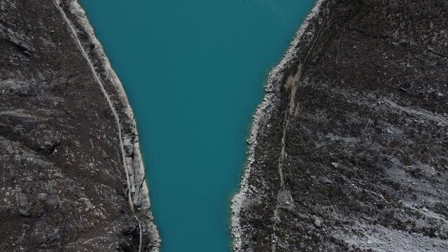 Camera looking down on the pale blue water of Laguna Paron panning up along the lagoon