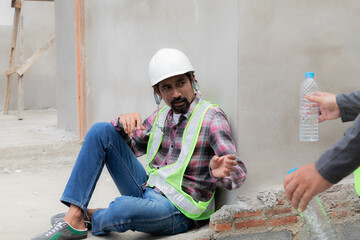 Two Asian builder workers wearing safety reflected vest and helmet tired thirsty hydrated drinking...