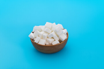 Fototapeta na wymiar Sugar cubes in a bowl on blue background