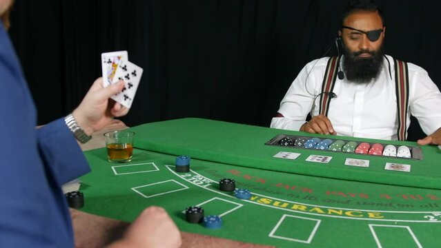 Man buying chips in a casino from a croupier dealer at a black jack poker table. The dealer has an eye patch