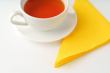 Cup of tea and paper napkin on white background