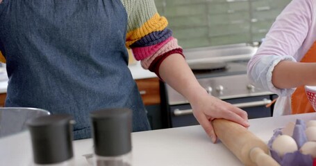 Happy biracial mother and daughter baking in sunny kitchen - Powered by Adobe