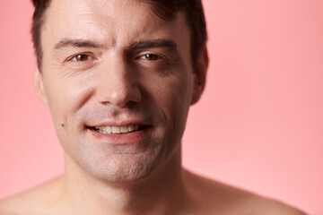 Fototapeta premium Portrait of happy middle-aged man standing against pink background