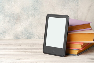 Digital tablet with a stack of books on gray background