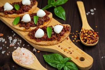 Bruschetta with dried tomatoes, mozzarella, garlic and olive oil. Traditional Italian cuisine sandwich made of grilled ciabatta. Antipasti