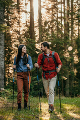 A couple clad in professional hiking gear makes their way through a mystical forest in pursuit of outdoor adventure