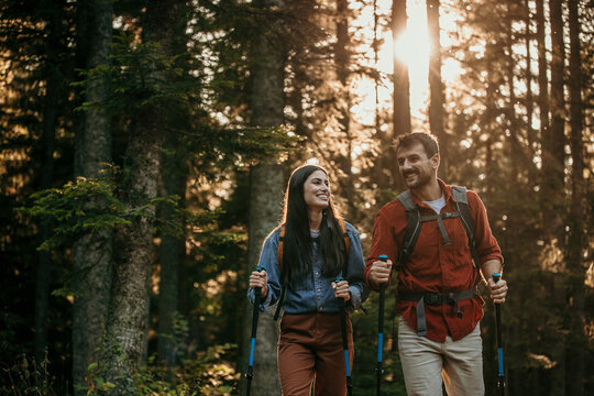 A pair of hikers, geared up and ready for action, pause for a moment to take in the breathtaking vistas of a remote mountain forest
