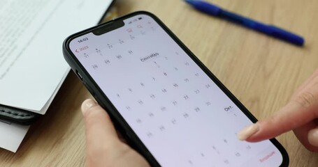 Closeup of businesswoman using calendar application on mobile device. Manager or SEO scrolling calendar screen on smartphone