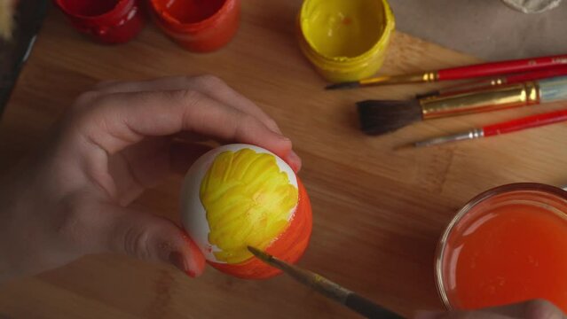  The child takes a white egg and paints it with bright colors