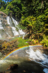 Rainbow in front of a waterfall on a rainy day. - 658061811