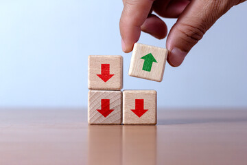 Hand places green wooden cube with up arrow. Facing opposite direction red arrow down Concept of...