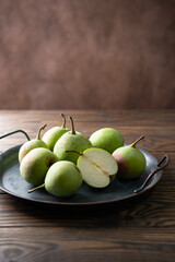 Ripe pears in a tray on a wooden table.