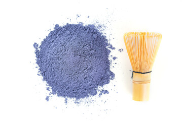 Heap of blue matcha powder from clitoria flowers with bamboo chasen on a white background.