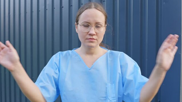 Young Woman in Blue Outfit Waving Hands Showing Emotion Gesture of Disallowed or Avoidance. Doctor or Scientist Refusing Entry with Hand Gestures While Shaking Head Against Blue Sheet Metal Background