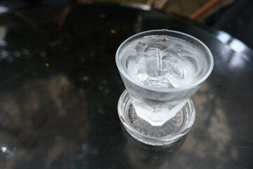 Glass of cold water with some ice on black table.