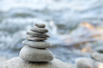 The stones of the pyramid balance on the bank of a mountain river. The subject is in focus, the...
