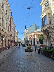 A landscape of pedestrian cobblestones surrounded by unique historical buildings of Chernivtsi against the background of a clear blue sky.
