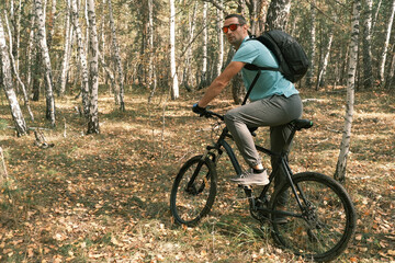 Fototapeta premium active lifestyle.A cyclist with a backpack is sitting on a bicycle in the autumn forest