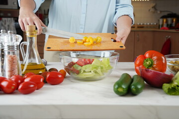 The woman in the process of making vegetable salad. Closeup of hands  cutting tomatoes on wooden table