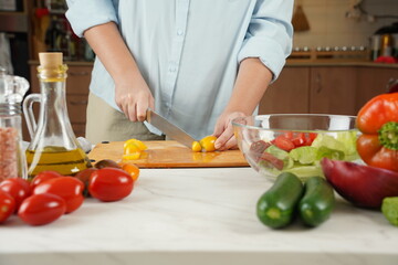 The woman in the process of making vegetable salad. Closeup of hands  cutting tomatoes on wooden table