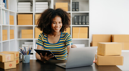Fototapeta na wymiar Small business entrepreneur SME freelance African woman working at home office, BOX,tablet and laptop online, marketing, packaging, delivery, e-commerce concept