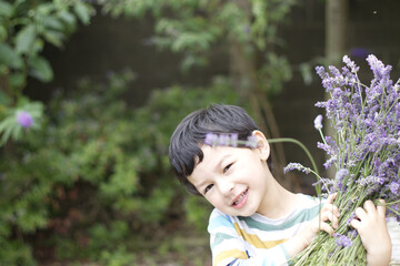 portrait of a little boy with flowers. Child holding a bunch bouquet lavenders. Child smiling face happy after cut lavender flowers. copy space.