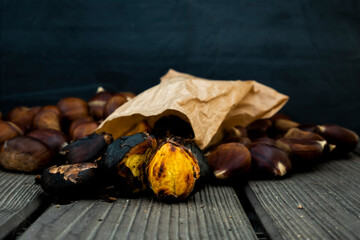 Roasted chestnuts in paper bags on a wooden background