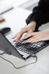 Close up of female hands typing on modern laptop keyboard making notes writing on device