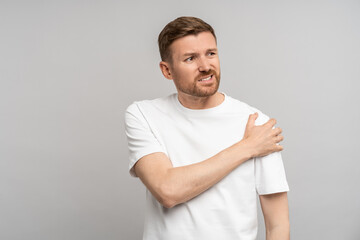Man touching hand shoulder feeling pain isolated on gray background after injury, trauma....