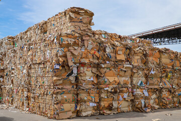 Bales of cardboard and box board with strapping wire ties before shredding at recycling plant