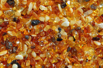 Natural gemstone amber texture background, small stones yellow orange gradient color. Natural mineral material for jewelry. Top view Amber texture. Aesthetic wallpaper, pieces ancient resin.