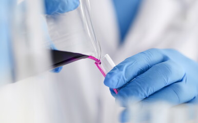 A male chemist holds test tube of glass in his hand overflows a liquid solution of potassium...