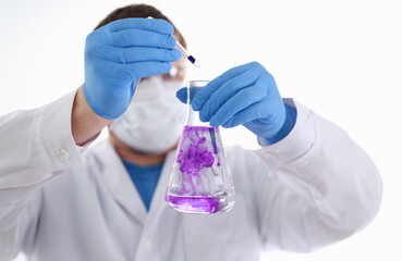 A male chemist holds test tube of glass in his hand overflows a liquid solution of potassium....