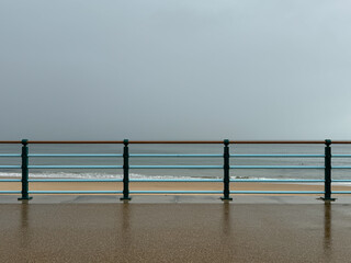 Retro seaside mint coloured handrail at walkway or promenade at the beach with golden beach and...