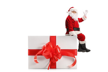 Santa Claus sitting on a present box and waving