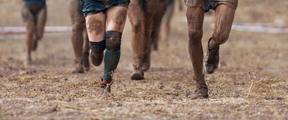 Group of participants in an obstacle course race running. They run very muddy. Concept of hardness...