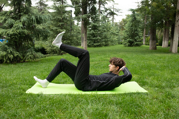 Man exercising outdoors in the garden sitting on a yoga mat. Exercise for health. Yoga.