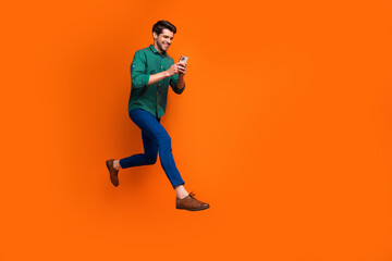 Fototapeta na wymiar Full body photo of funky young business guy success businessman running with smartphone fast specialist isolated on orange color background