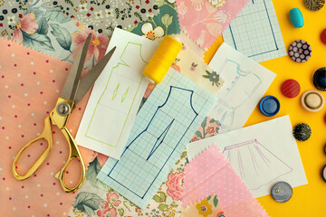 Fabric, tailor's scissors and patterns for sewing clothes. Buttons, fabric, clothing sketches, threads are items for designing and sewing clothes. Sewing process.
