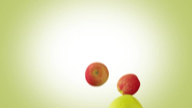 Green and red apples falling down in slow motion on green background.