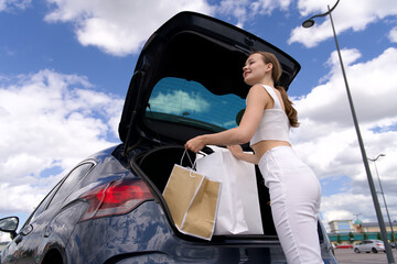 Young woman carry her bags in a car trunk after shopping in mall