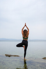 Woman practicing yoga by the sea on the rocks