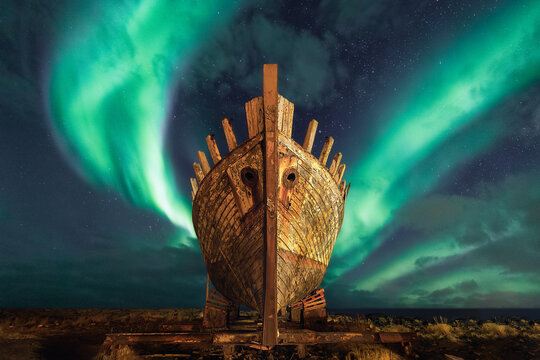 Northern Lights (Aurora Borealis) dancing across the sky over an old Viking ship, Akranes, Borgarfjardar, Iceland