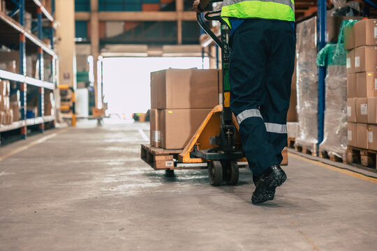 Warehouse staff moving load parcel box with Hand pallet truck or Hand lift manual delivery shipping goods in shelf storage area.