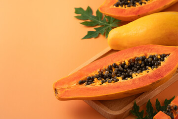 Fresh tropical cut papaya fruit over orange table background.