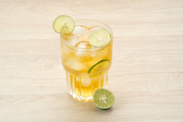 Fototapeta premium Iced tea with lime on a wooden table, refreshing drink 