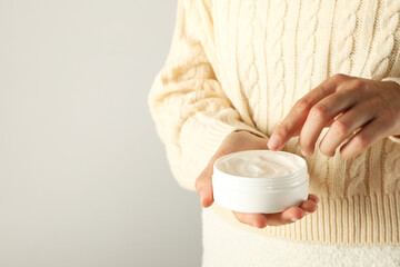 Jar of cream in female hands on light background, space for text