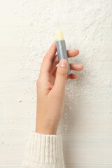 Lip balm in female hand on light background, top view