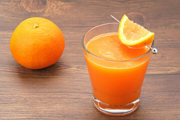 Orange juice in glass, cold pressed juice with fresh fruits on wooden table
